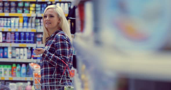 Attractive Woman is Walking Near the Supermarket Shelf and Selects the Products alt