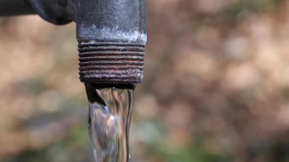 Close up shot of a rusty fountain with crystal clear water in slow motion. alt