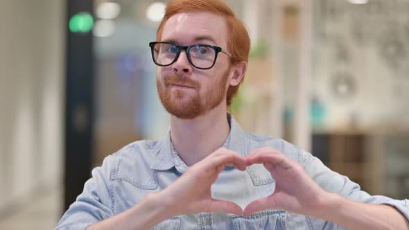 Portrait of Loving Casual Redhead Man Showing Heart Sign  alt