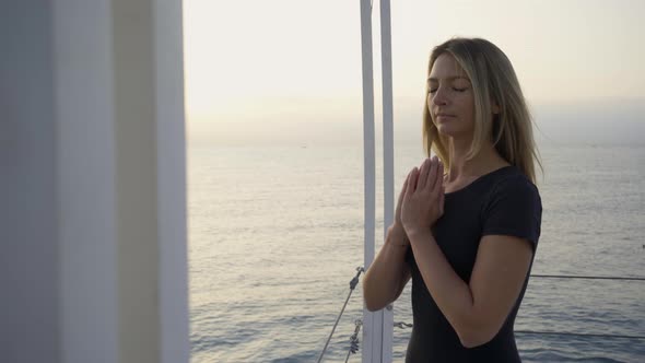 Pretty Woman Prays Holding Hands in Namaste on Empty Pier