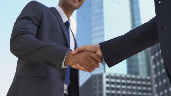 Low angle view of two male business partners shaking hands