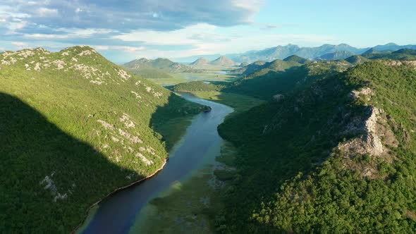 Bends and curves of blue river flowing through green valley toward distant mountains. alt