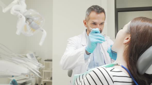 Mature Male Dentist Examining Teeth of a Female Patient