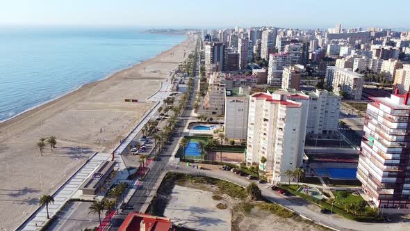 Aerial drone footage of high buildings with swimming pools near the sea and beach of San Juan, Spain alt