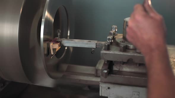 The Turner Processes the Metal Part on a Lathe in a Lathe Shop alt