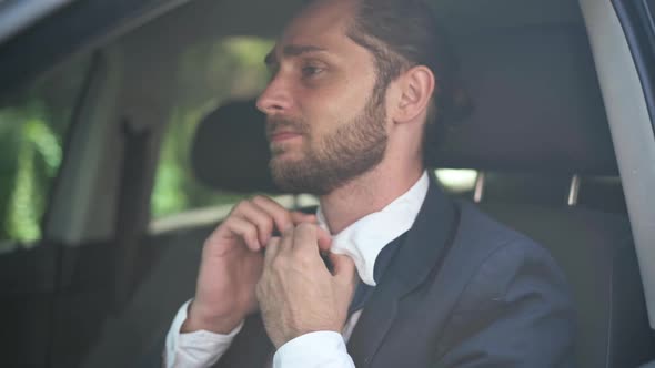 Troubled Stressed Man Loosening Necktie Unbuttoning Shirt Sitting in Sunshine on Driver's Seat alt