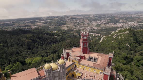 Aerial circular pan shot around the decorative clock tower of Pena palace in Sintra Portugal alt