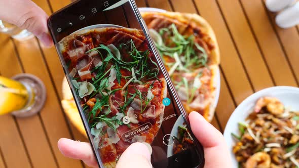 Man's Hands Hold a Cell Phone and Take Photos of Italian Food for Social Media alt