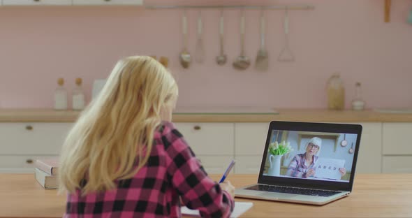 School Child Studying Online with Senior Female Teacher on Laptop Screen. Little Girl Has Online alt