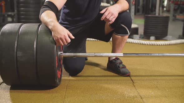 Portrait of Brutal Powerful Bodybuilder Sitting Near Heavy Barbell alt