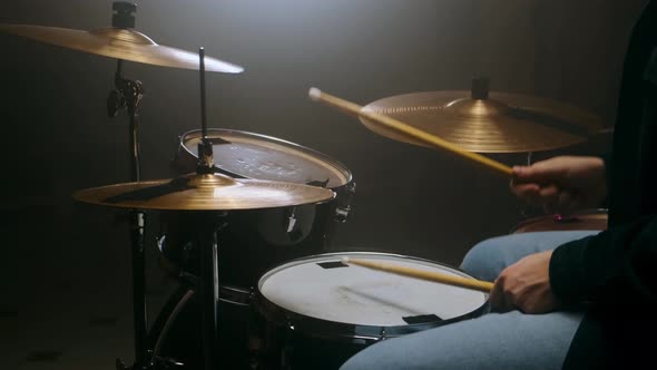 Drummer Playing the Drum Set in a Dark Room on a Black Background alt