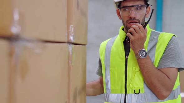 Professional Cargo Worker Talks on Portable Radio to Contact Another Worker alt