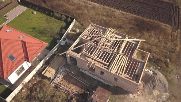 Top down aerial view of two private houses, one under construction with wooden roofing alt
