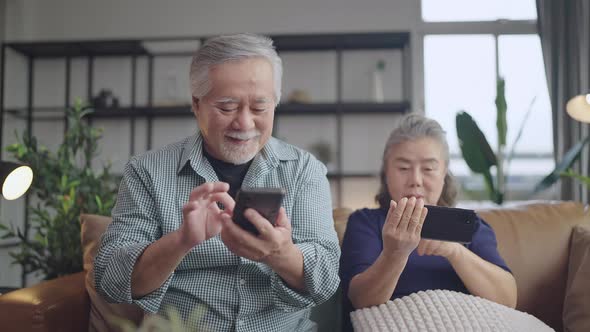 happiness asian retired couple enjoy playing and competition game smartphone mobile online together