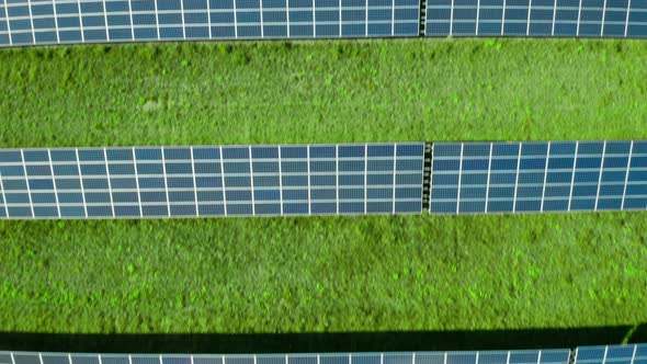 Flight Along Solar Panel on the Green Field. Solar Power Station for Production of Green Energy alt