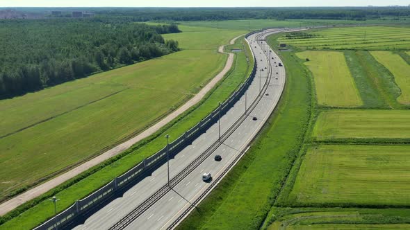 Asphalt Speedway with Cars Through Green Field. Aerial View From Drone alt