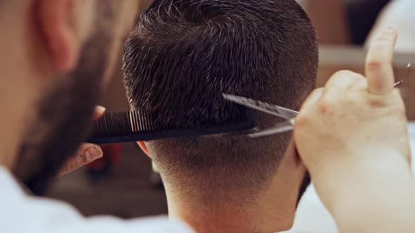 Barber Doing a Haircut to Male Client in Barbershop Close Up