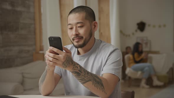 20s Tottoed Asian Father Swiping on His Smartphone with Various Facial Expressions alt