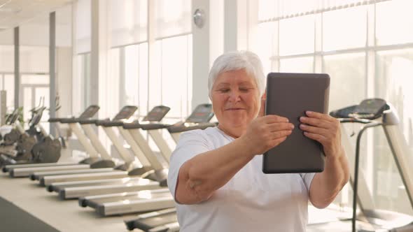 An Elderly Woman is Photographed on a Tablet Video Call Rest After Training Sends Greetings to alt