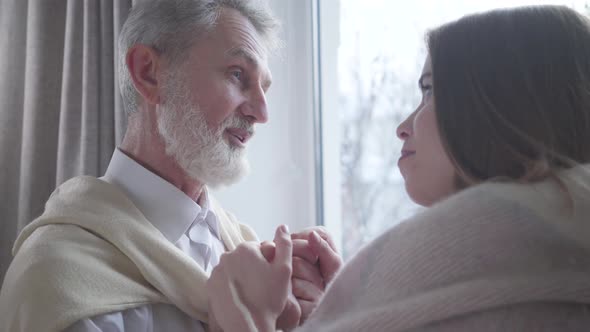 Portrait of Excited Senior Caucasian Man in Love Talking To Young Smiling Woman Indoors. Positive alt