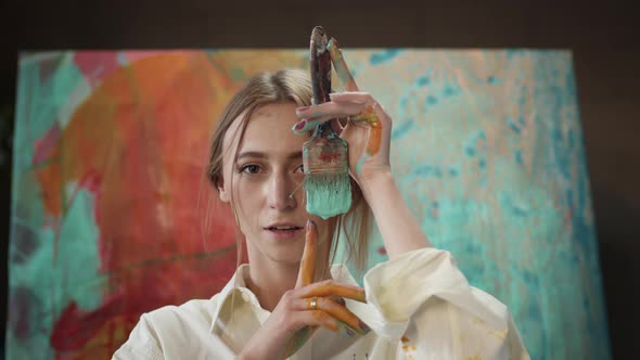 Young Artist In Art Studio With Brush In Her Hands. alt