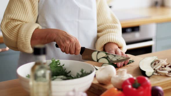 Hands of Woman Chopping Zucchini on Kitchen