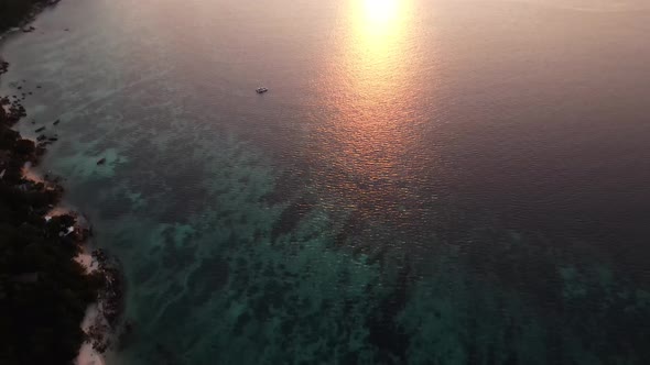Aerial Tilt Up Over Koh Lipe To Reveal Golden Orange Sunset Over  Strait of Malacca. Establishing Sh alt