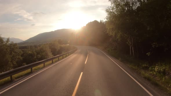 Driving a Car on a Road in Norway at Dawn alt