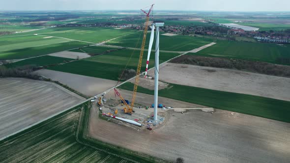 Wind turbine assembly, crane lifts the propeller. Windmill producing electricity under construction.