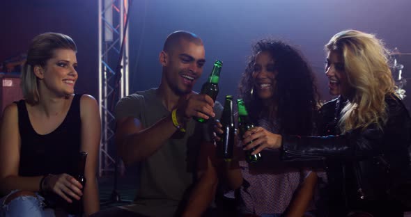 Group of friends toasting beer bottles at a concert 4k alt