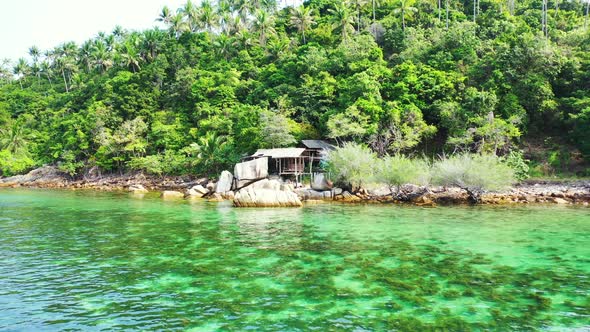 Coral reefs growing on white sand of sea bottom under calm clear water of lagoon washing rocky coast alt