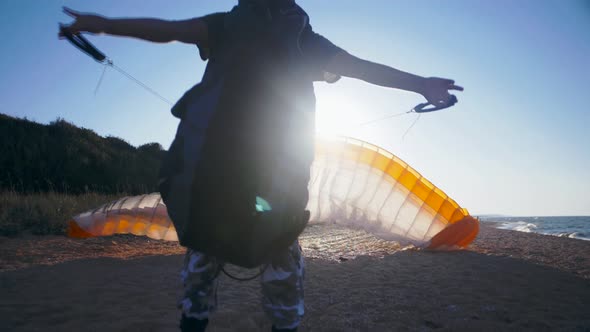 Parachutist folds a paraglider on a sandy beach. Sunset. Extreme sport