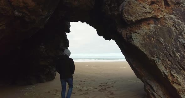 Male Walking Slow Motion Out of the Cave to the Ocean alt