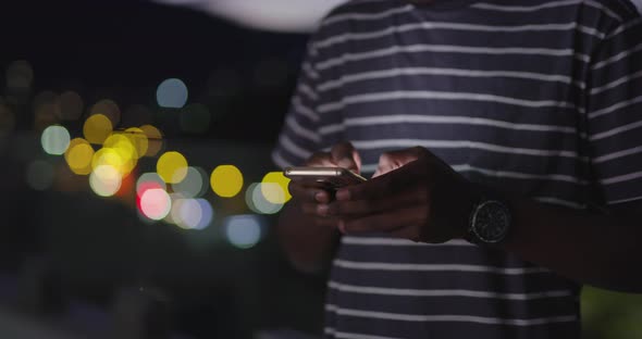 Afro American Man Using Smartphone in Night City Lights Backgorund alt