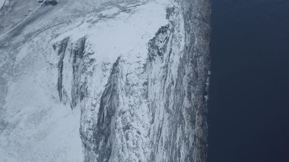 Aerial view overlooking the snowy Segla mountain, winter day in Senja, Norway - rising, drone shot alt