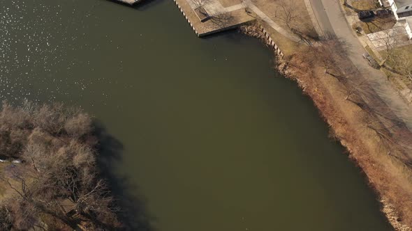 An aerial shot of a pond in a suburban neighborhood on Long Island, NY.  The camera tilted down, pan alt