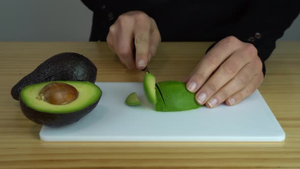 Young woman cutting a green avocado