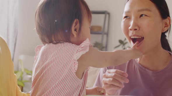 Lovely Asian Baby Girl Feeding Mom during Meal alt