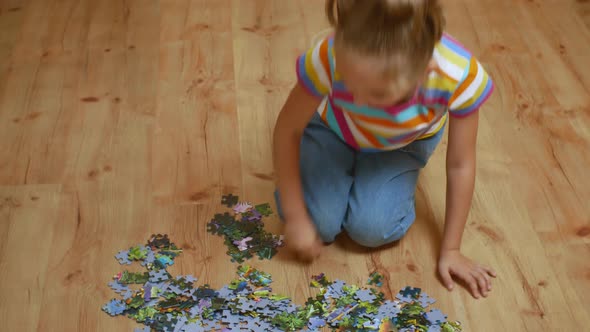 A Little Girl on a Wooden Floor Enthusiastically Collects Puzzles