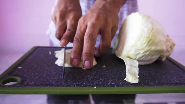 Young man cutting cabbage for salad alt