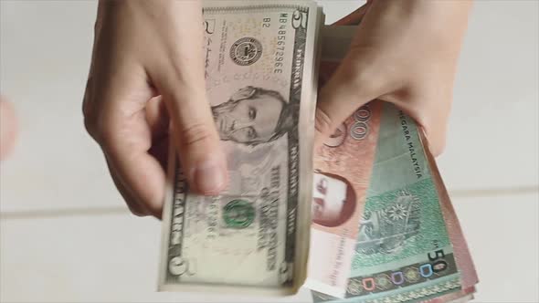 Woman traveler's hands recounts her cash money in different currencies alt