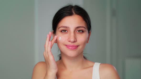 The Girl Applies the Cream to Her Face with Her Hand