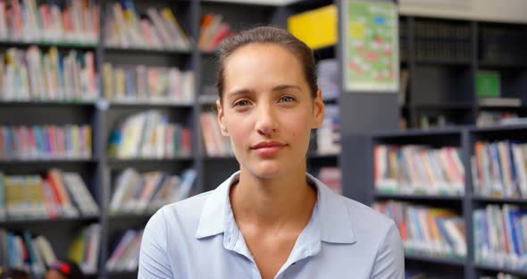 Front view of Caucasian female teacher standing in the school library 4k alt