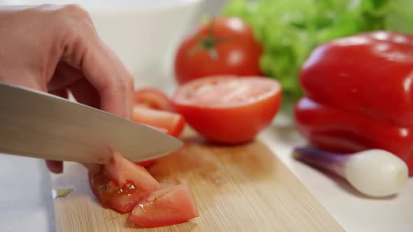 Woman's Hands Using Kitchen Knife Cutting Fresh Tomato on Wooden Cutting Board