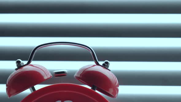 Red alarm clock close up, ringing early morning against background closed blinds alt
