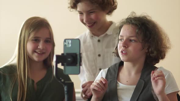 Three Schoolchildren are Filming a Video Using a Smartphone and a Steadicam alt