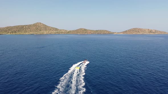 Aerial View of a Motor Boat Towing a Tube. Elounda, Crete, Greece