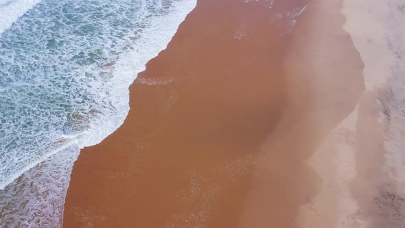 Aerial Drone Shot of Sandy Beach Waves Breaking on Shore, Vertical Top Down View of Golden Sand and alt