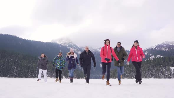 A group of happy people running and laughing over a frozen Black lake in Durmitor, Montenegro