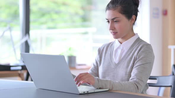 Attractive Indian Woman Thinking and Working on Laptop at Work  alt